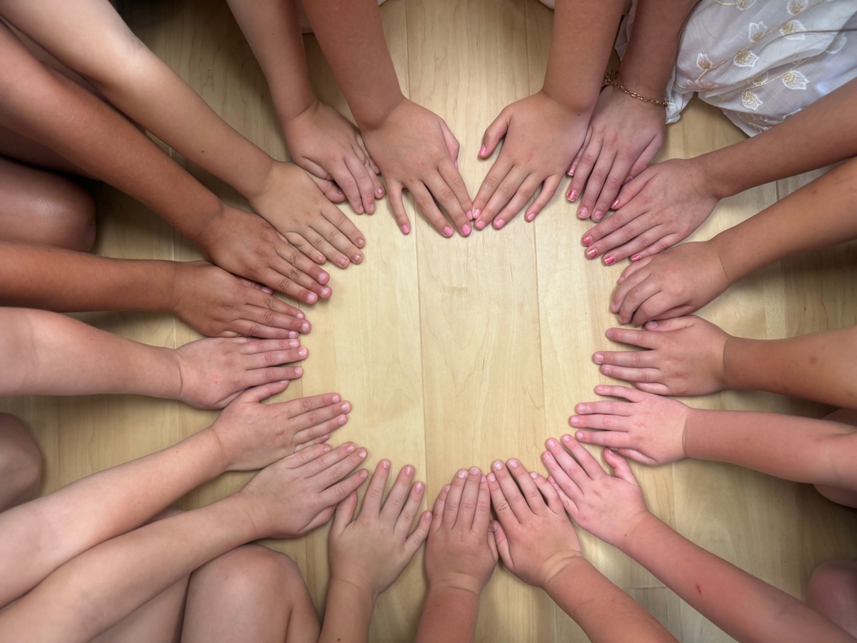 Kids' hands forming a heart on the classroom floor