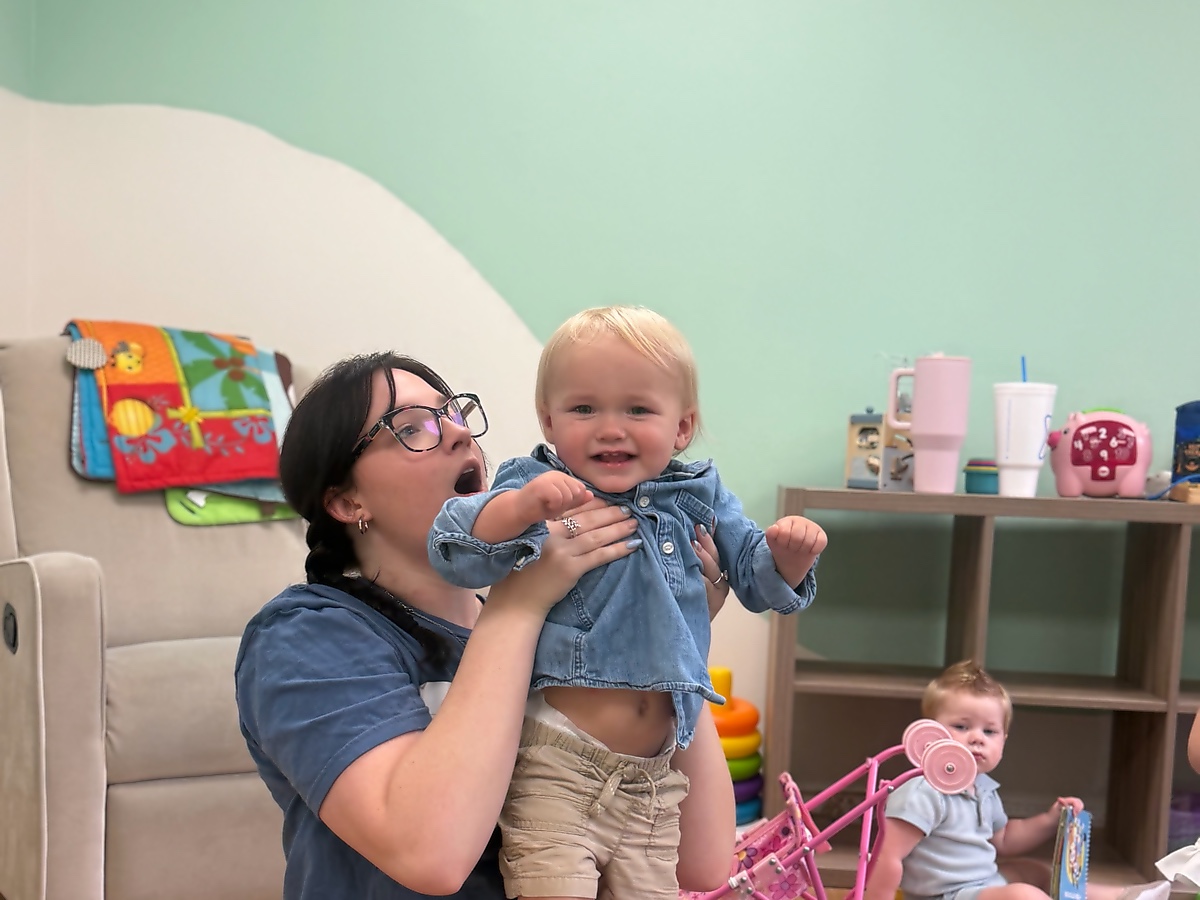 A volunteer holding up a smiling baby in the Sojourn Kids nursery
