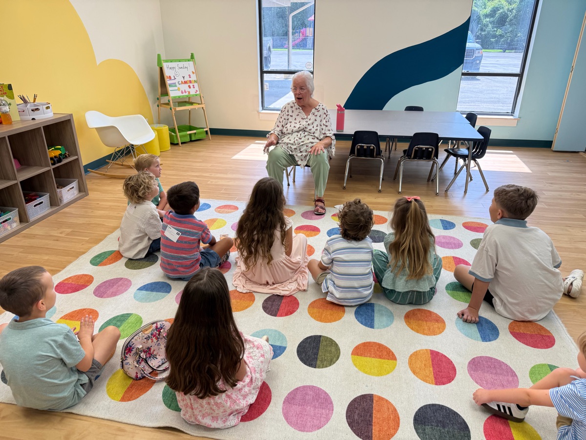 A teacher leading a lesson for Pre-K and kindergarten kids seated on a colorful rug